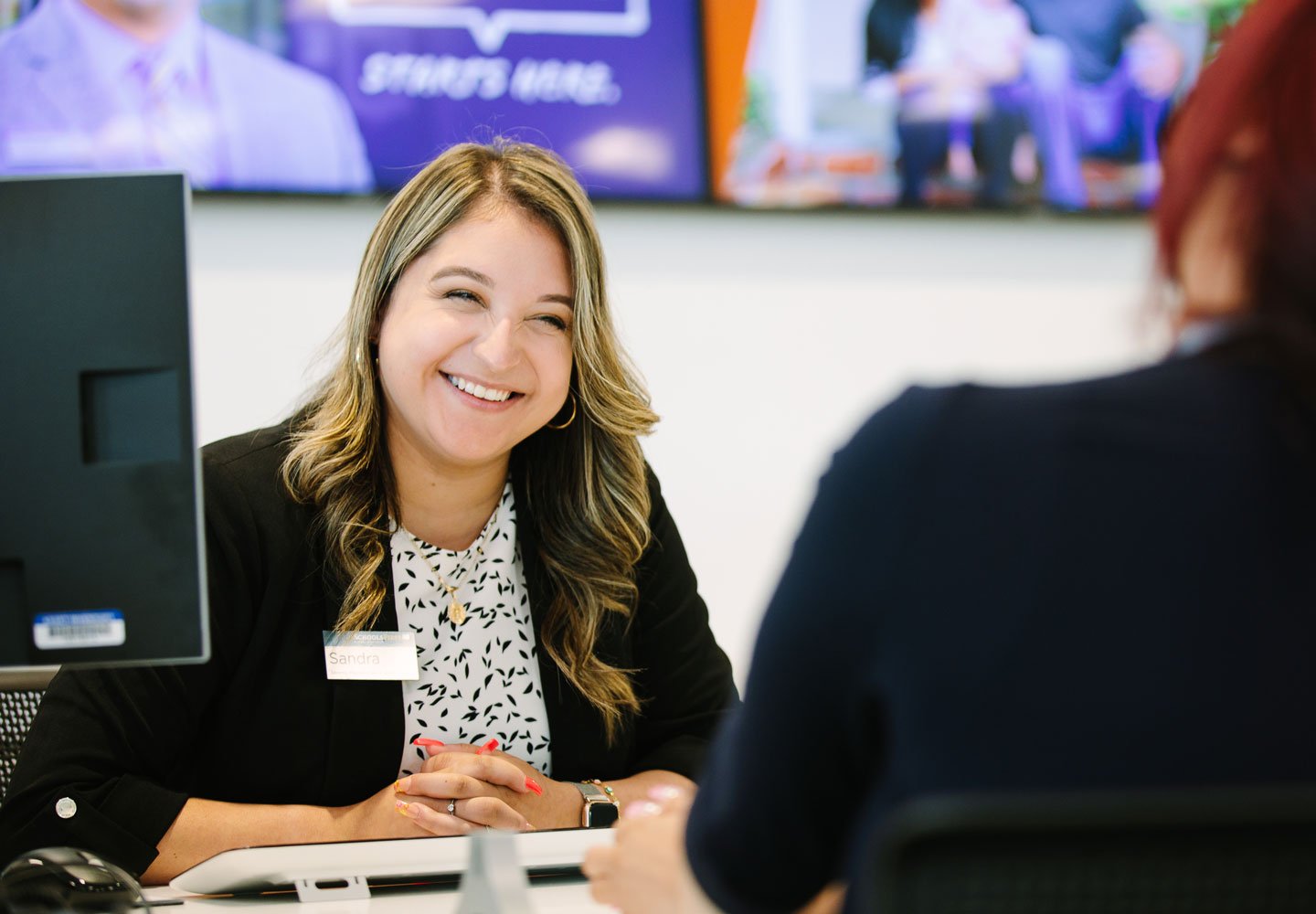 Photo of a SchoolsFirst FCU teammember at a desk helping a Member.