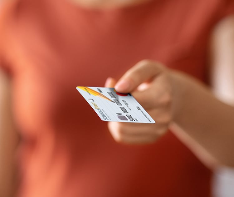 A person holding a SchoolsFirst FCU debit card in hand.