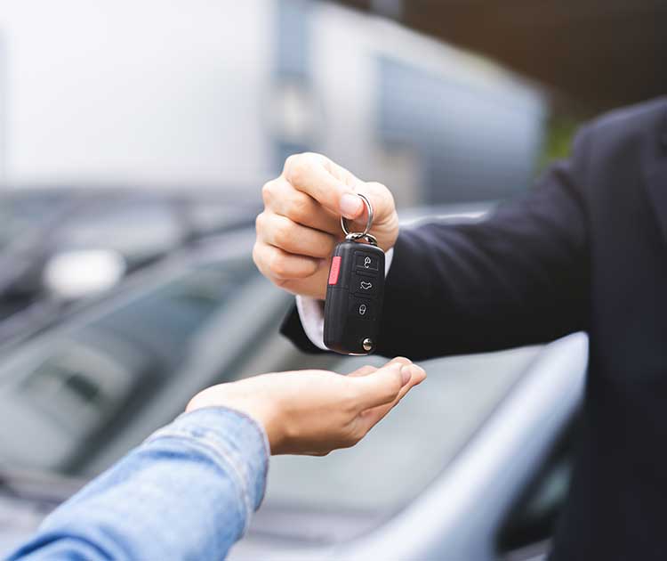 A car dealer handing car keys to buyer.