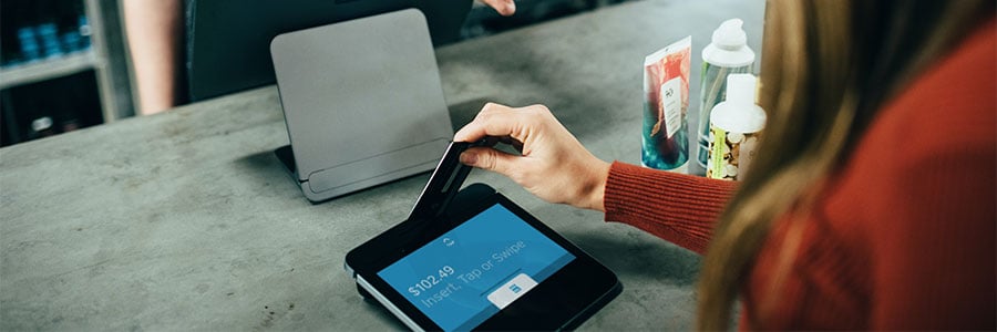 Image of a person performing a card transaction at a retail purchase terminal.