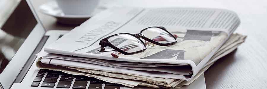 Newspaper with computer on table.