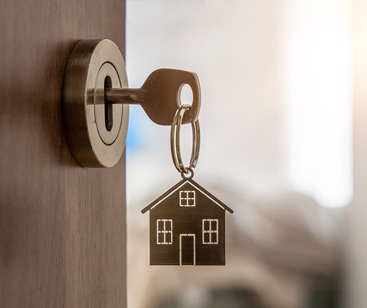 Open door to a new home with key and home shaped keychain.