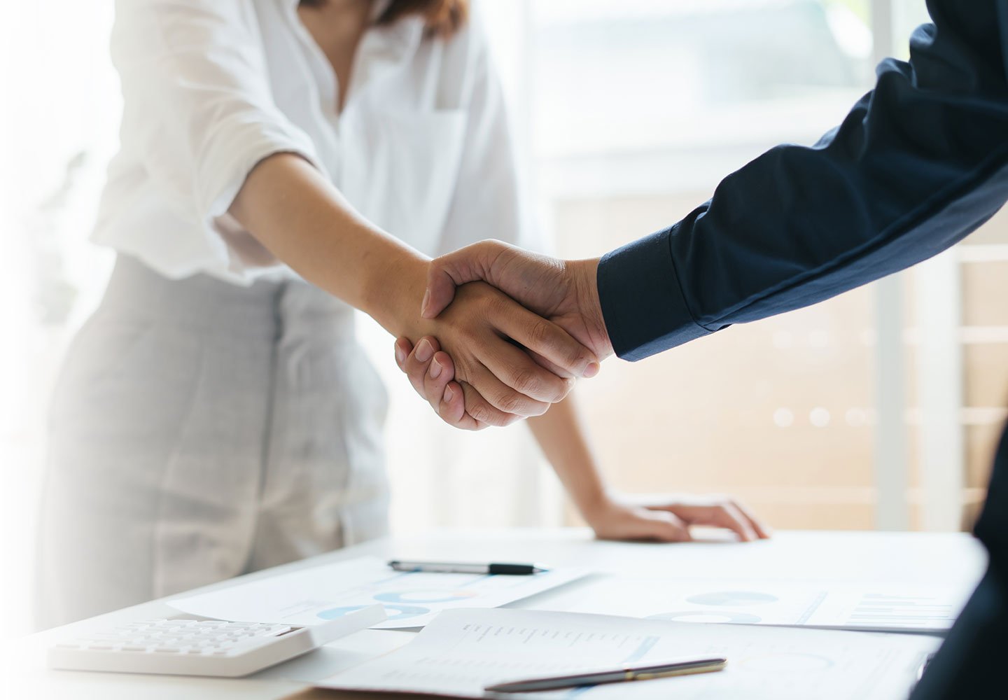 A male and female business persons shake hands.