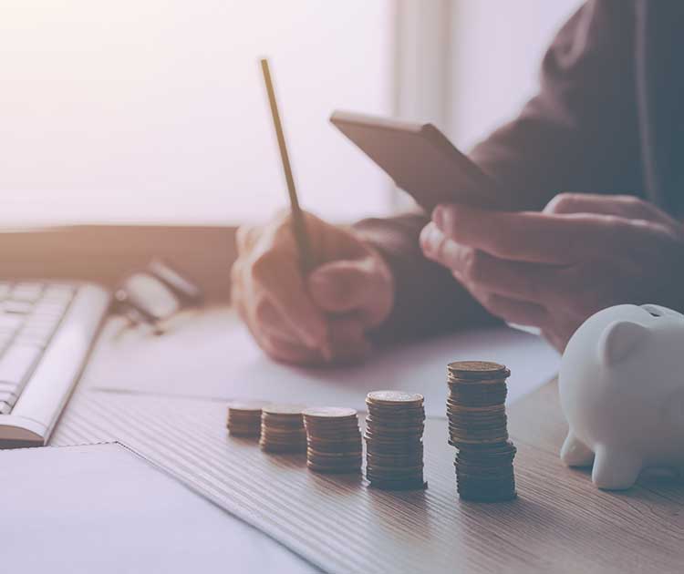 Desk with coins and person calculating budget.