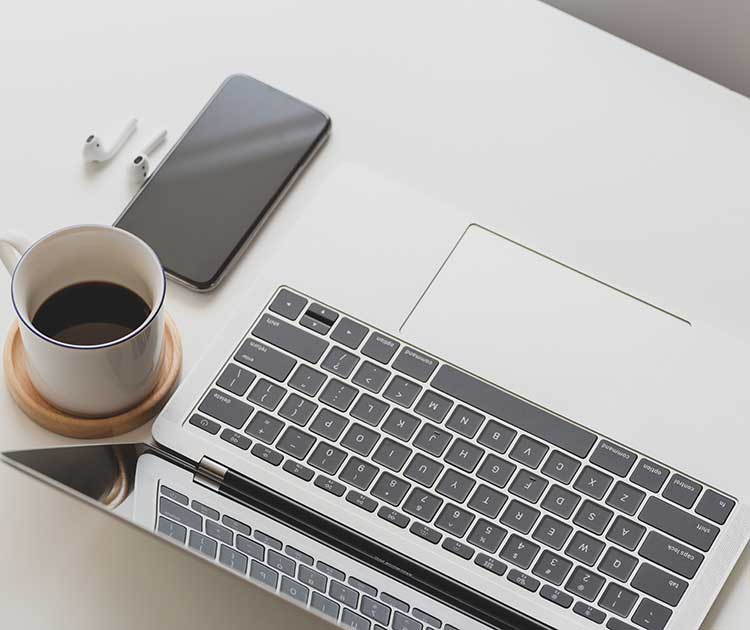 Overhead photo of desk with laptop, mobile device and coffee.